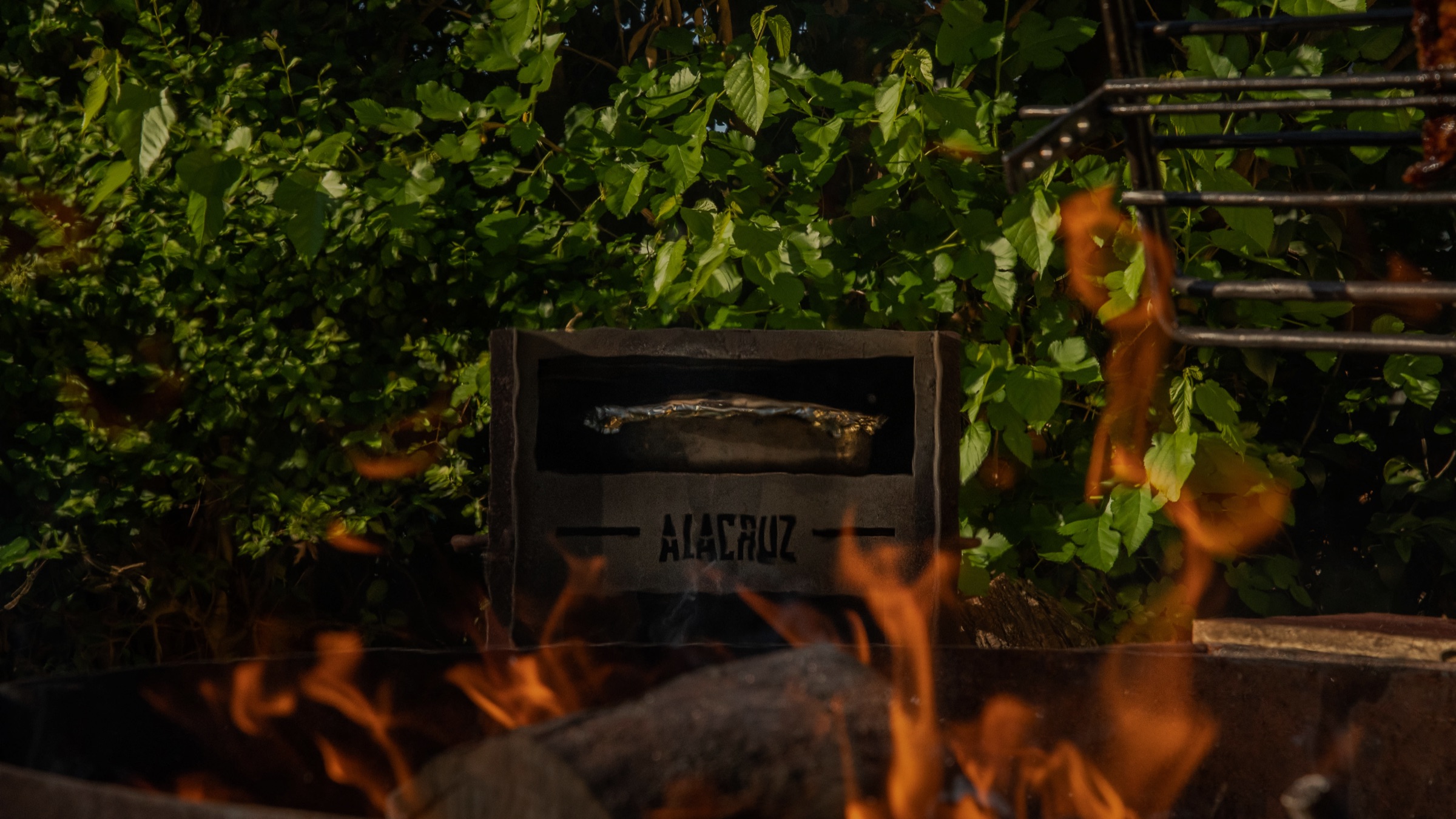 Firewood burning down in the side brasero of a grill